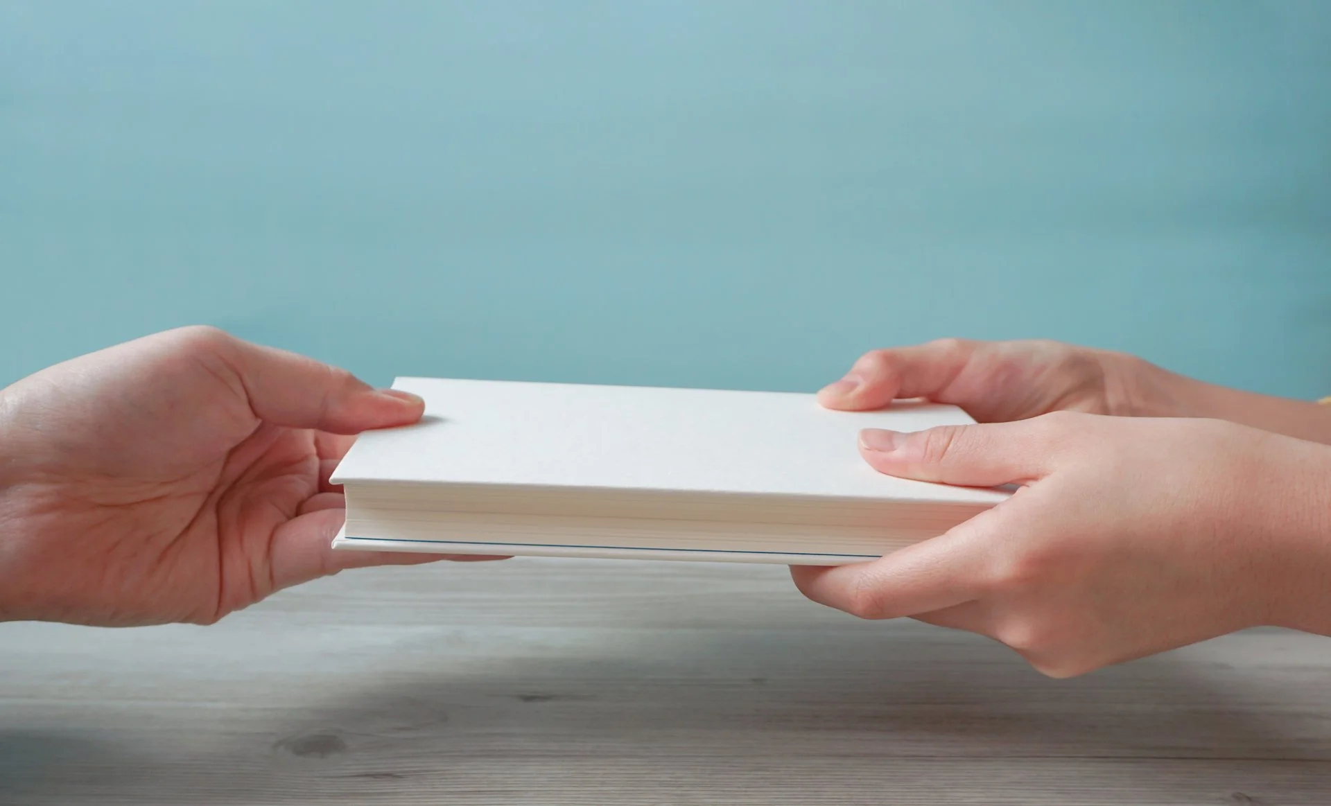 二人の手で一冊の本を手渡す様子
