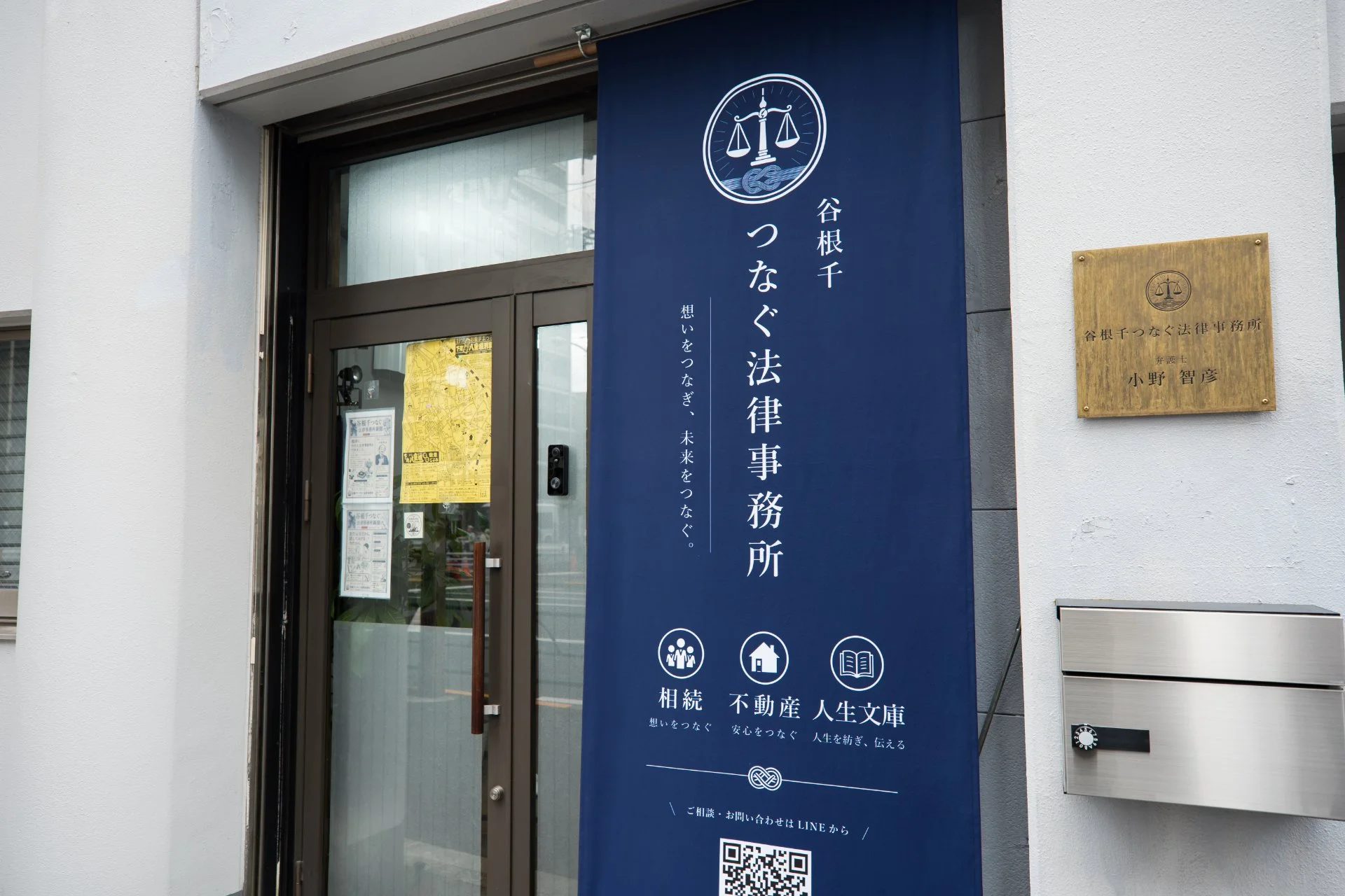 谷根千つなぐ法律事務所の入口に掲げられた紺色の看板と真鍮の表札